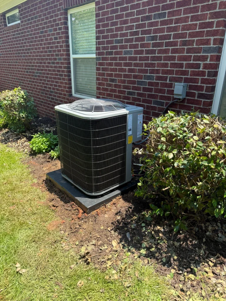 Picture of a residential AC unit next to a brick wall