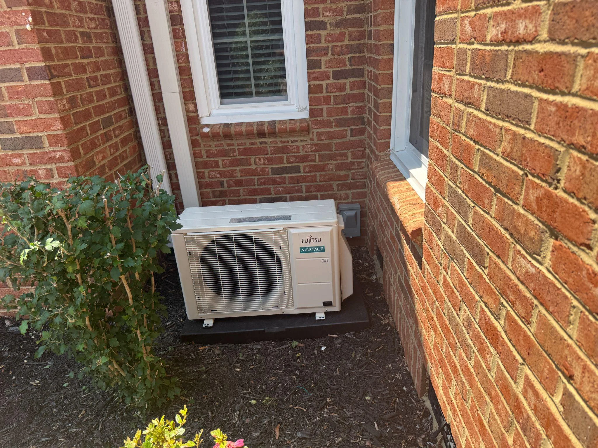 picture of a fujitsu mini split heat pump unit installed outside a brick wall