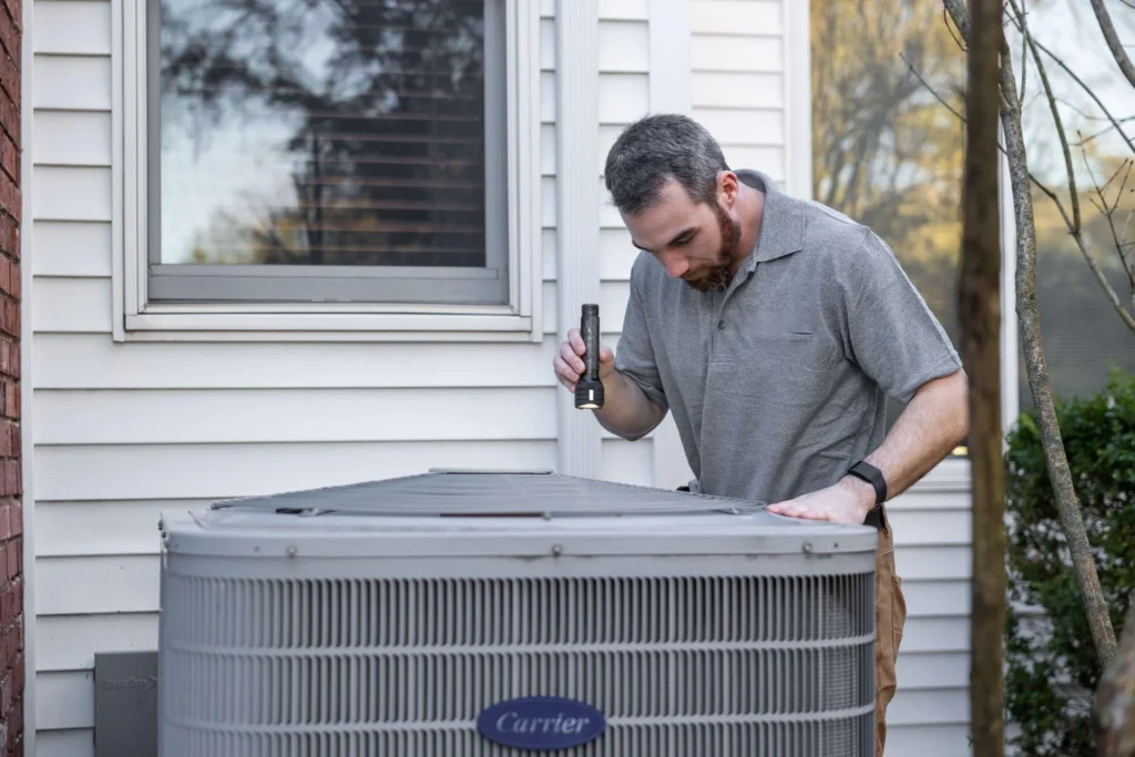 picture of a man inspecting an ac unit with a flashlight