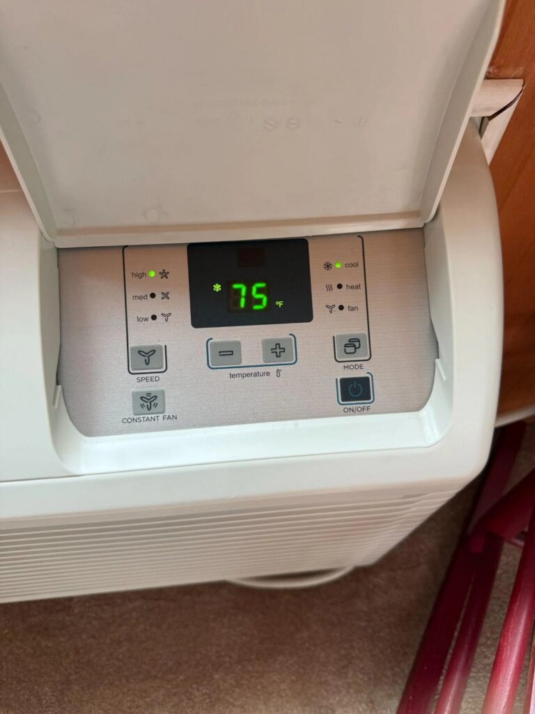 Picture of a white wall mounted air conditioner control panel showing 75 degrees