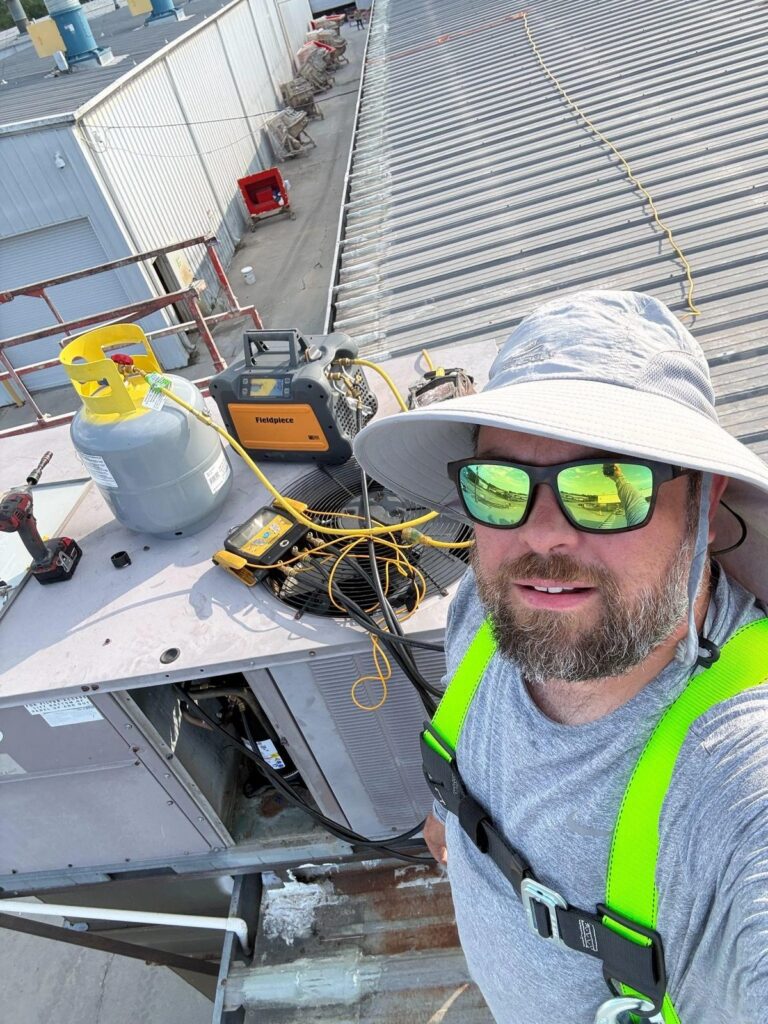 Picture of an HVAC technician working on a rooftop AC unit